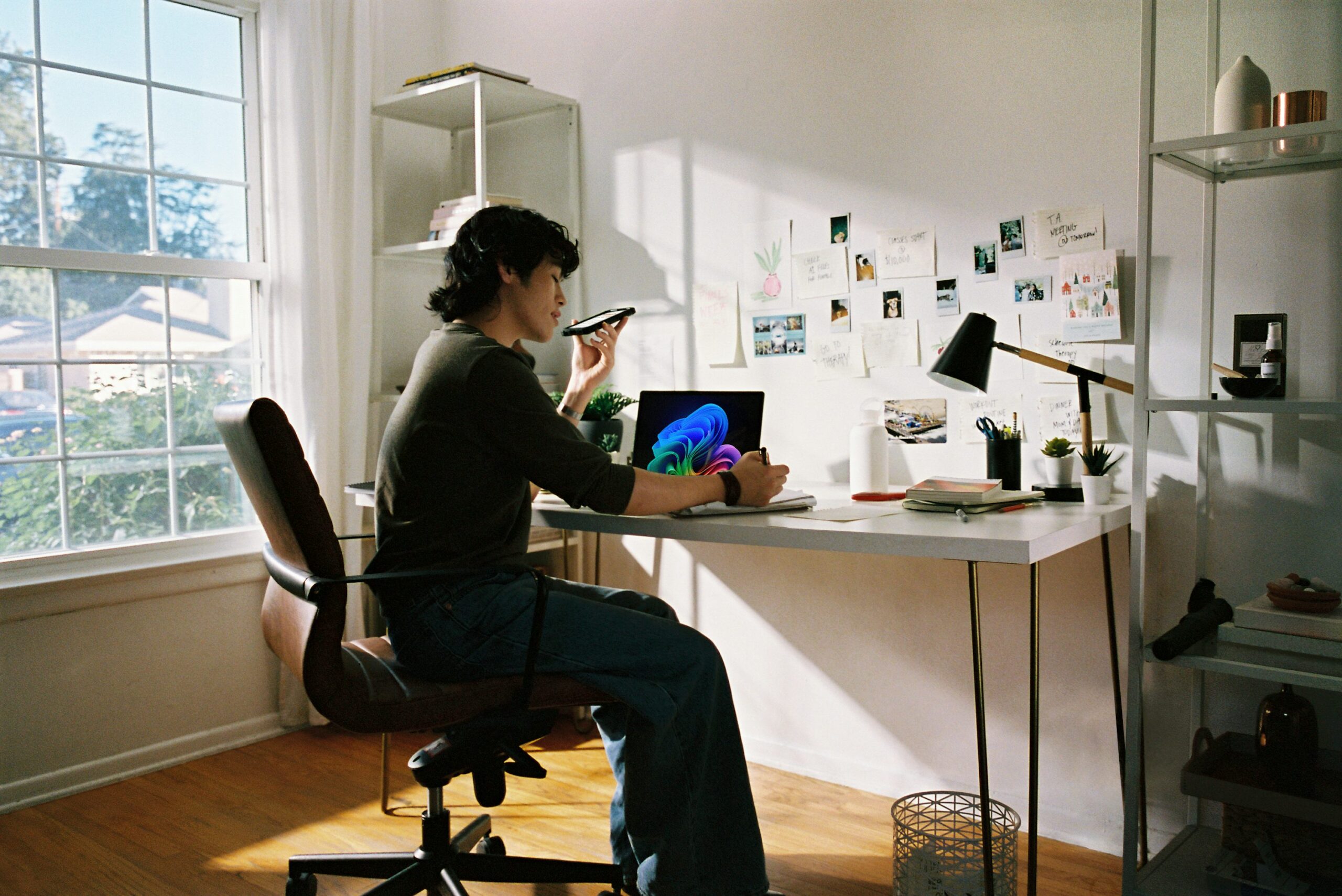 A freelancer works at a bright home office desk with an open laptop displaying colorful software, representing modern AI-assisted productivity.